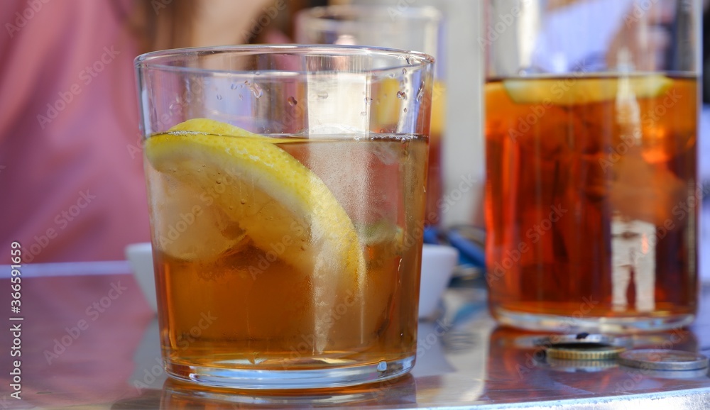 Vaso con bebida fría con hielos y limón en una terraza