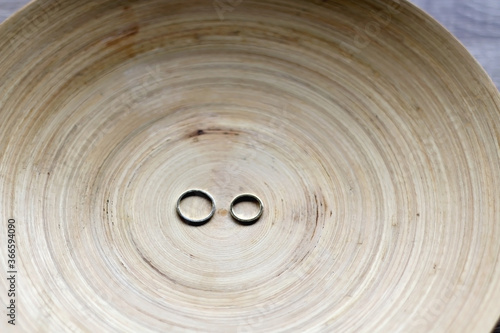 Gold wedding rings on rustic wooden plate. Selective focus.