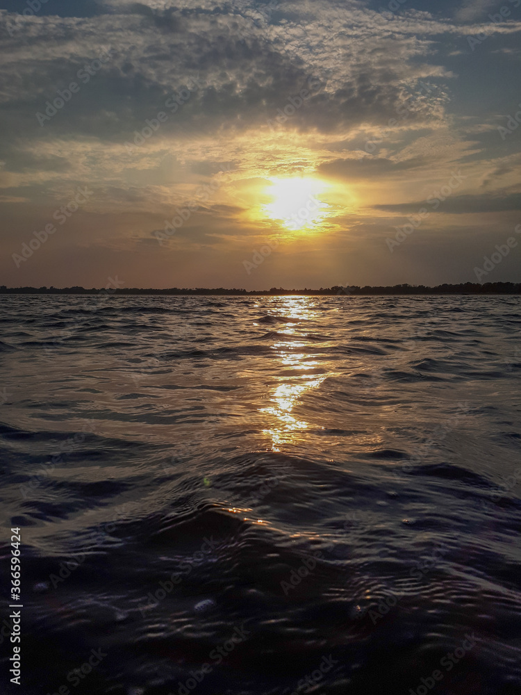 Fototapeta premium Scenic view of ocean waves in motion against sunset sky with reflections in Grado, Italy. 