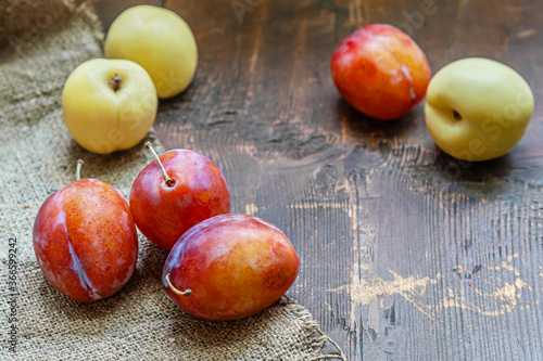 still life of ripe red plums and white nectarines on a wooden table