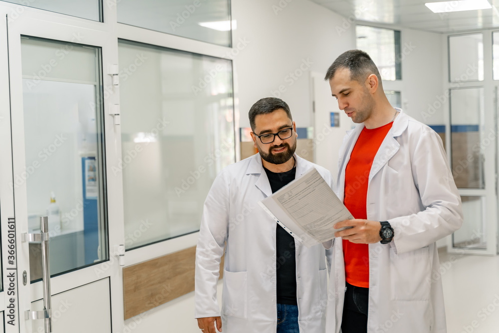 Obraz premium Doctors are discussing medical issues. Standing at hospital with papers in hands.