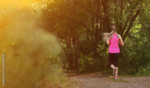 Young fitness woman running in the morning forest trail. Healthy fit living.