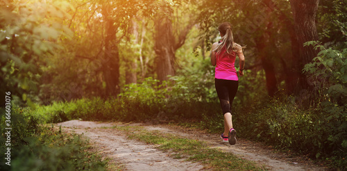 Young fitness woman running in the morning forest trail. Healthy fit living.