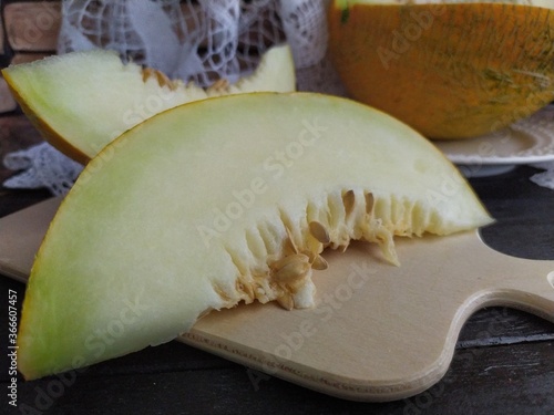 Large pieces of cut melon with seeda on a wooden table photo