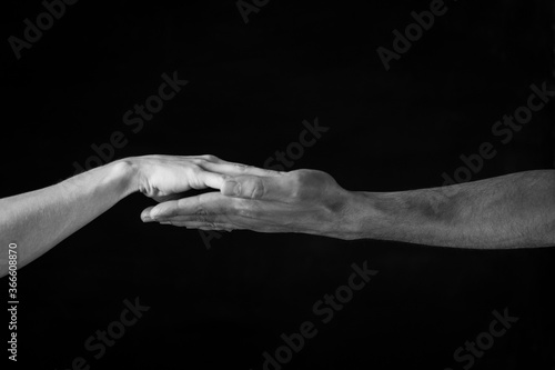 male and female hands touch each other on a dark background. close up. black and white photo