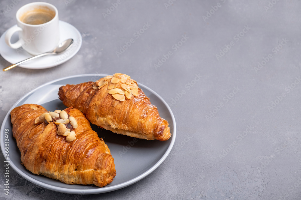 Crispy croissants with almond flakes and cup of coffee. Morning breakfast concept. Text space