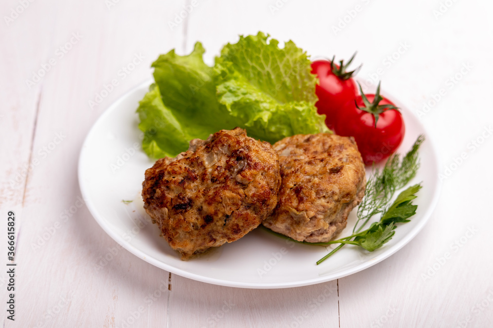 meatballs with vegetables on a white plate on a white wooden background