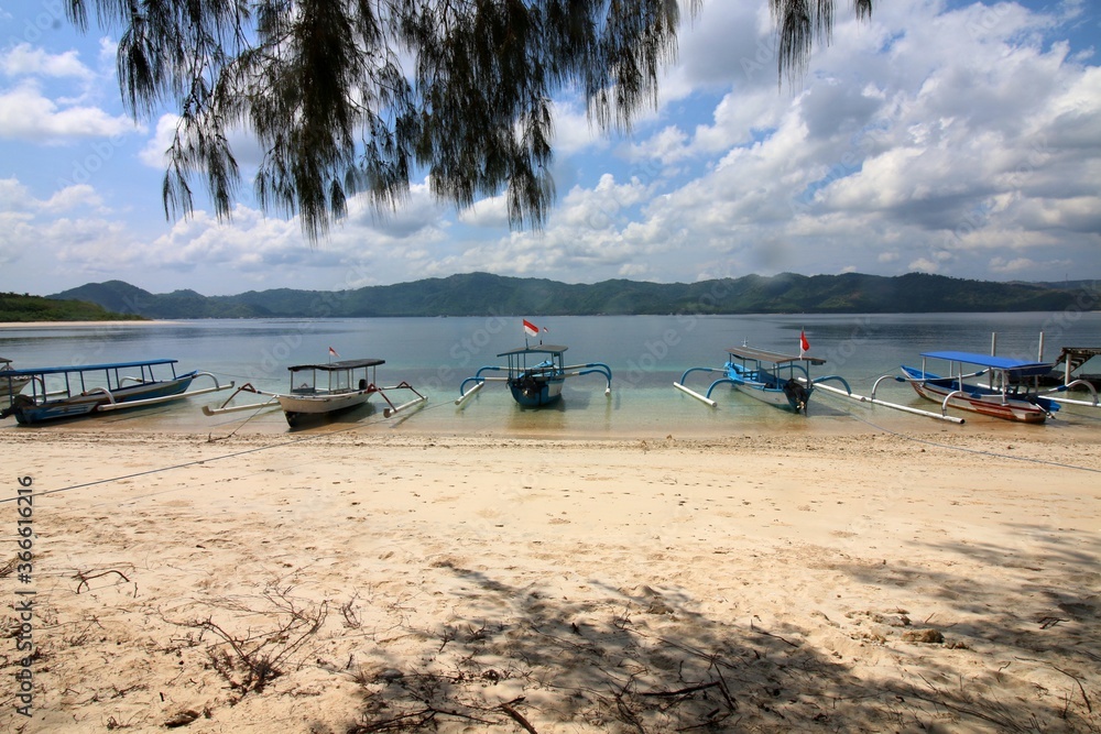 traditional boats at sandy beach with view to mainland, blue sky with white clouds