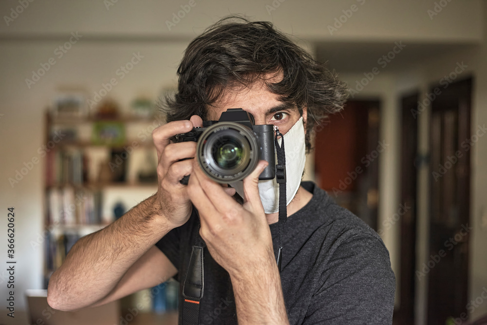 Photographer with face mask taking a photo inside his house. Photographer with face mask taking a photo inside his house.