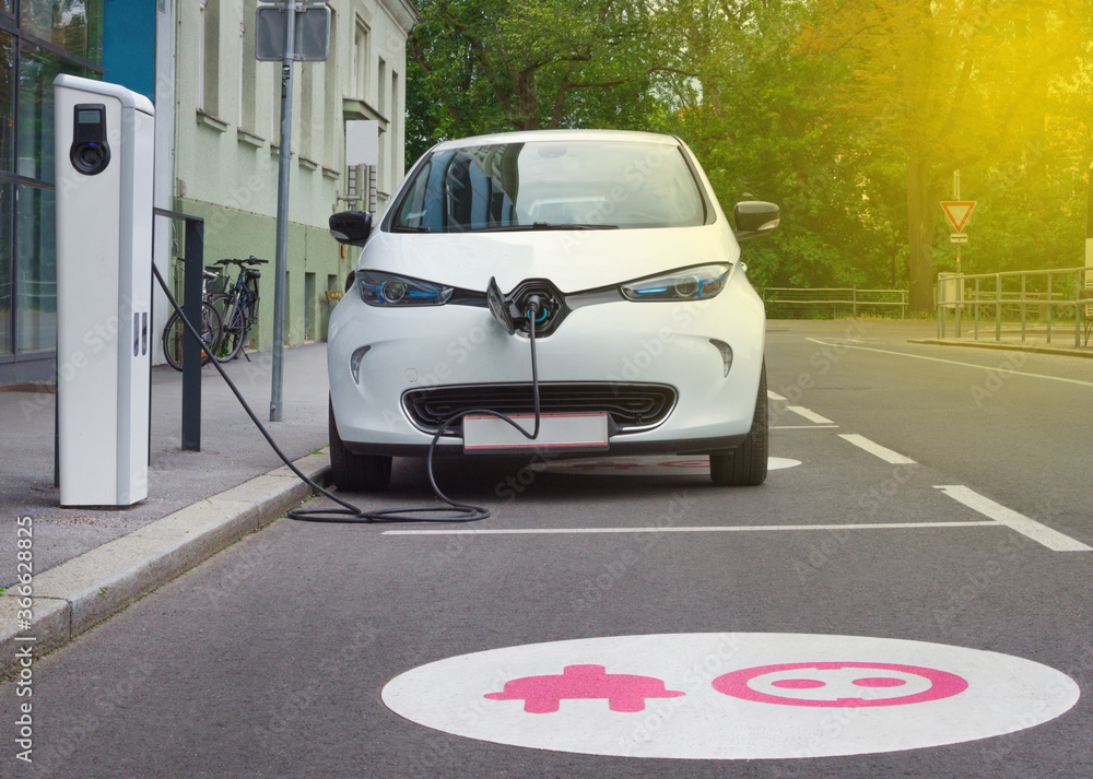 Fototapeta premium Nowoczesny samochód elektryczny podłączony do ładowania na stacji ulicznej. Nowe pojazdy energetyczne, przyjazne dla środowiska alternatywne źródła energii dla samochodów