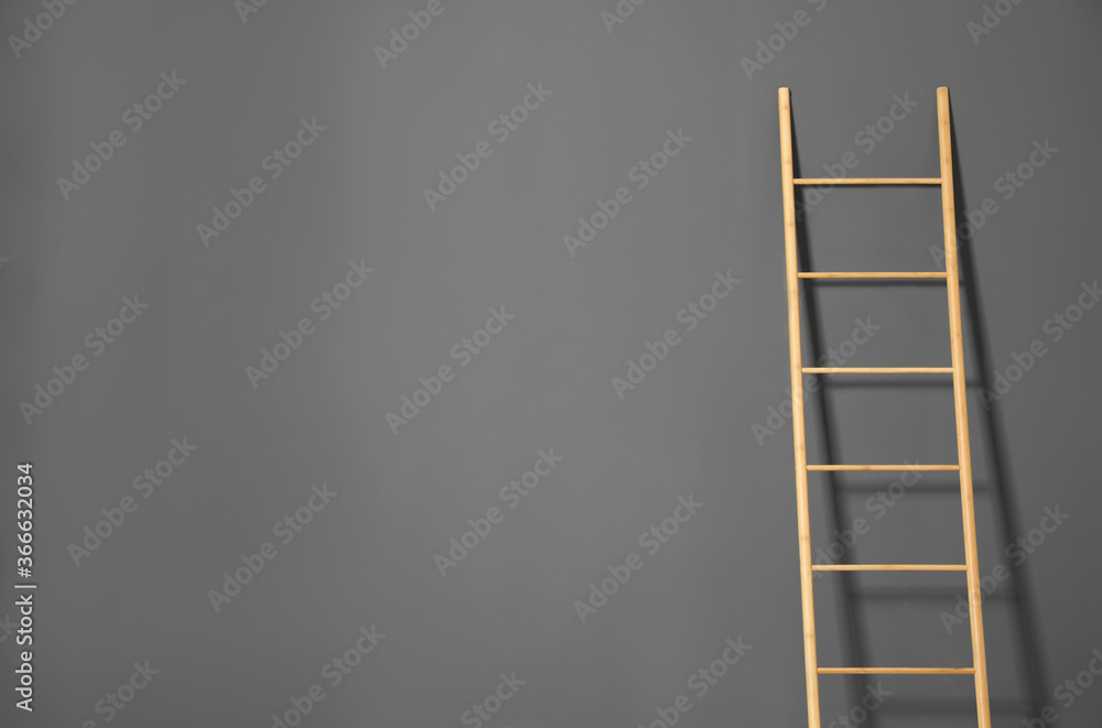 Modern wooden ladder on grey background. Space for text