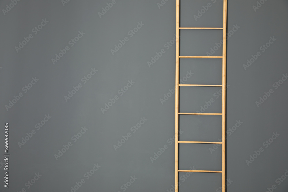 Modern wooden ladder on grey background. Space for text Modern wooden ladder on grey background. Space for text