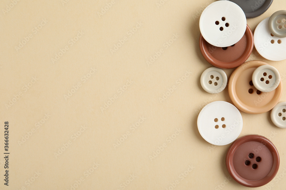 Many colorful sewing buttons on beige background, flat lay. Space for text Many colorful sewing buttons on beige background, flat lay. Space for text