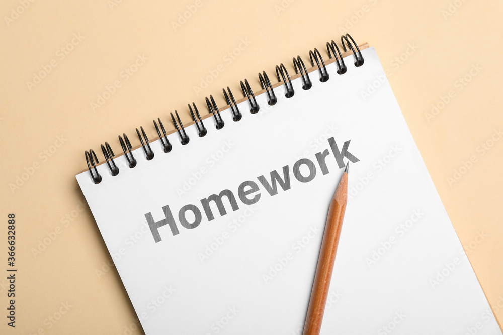 Notebook with inscription HOMEWORK and pencil on beige background, top view Notebook with inscription HOMEWORK and pencil on beige background, top view