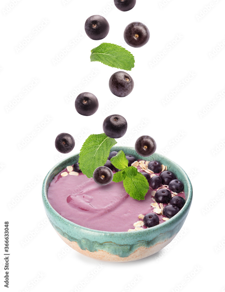 Acai berries and mint falling into bowl on white background Acai berries and mint falling into bowl on white background