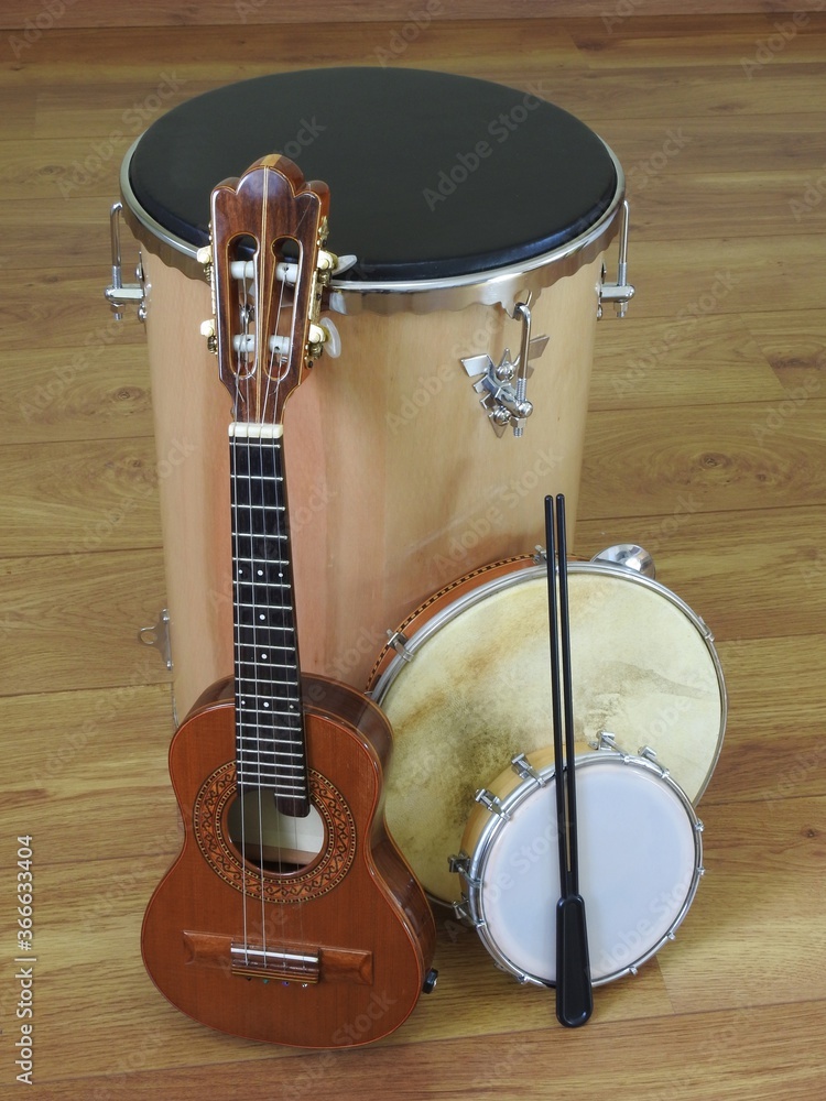 Four Brazilian musical instruments: “tantan” (or “rebolo”), cavaquinho,  pandeiro (tambourine) and tamborim with drumstick, on a wooden surface.  They are widely used in samba and pagode ensembles. foto de Stock | Adobe