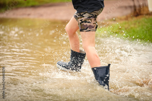 Canvas Print Boy walking through flooded creek wearing gumboots getting very wet, no face vis