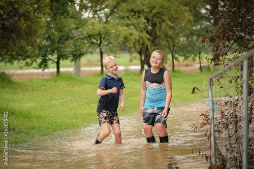 Happy kids playing in floodwater on rainy day