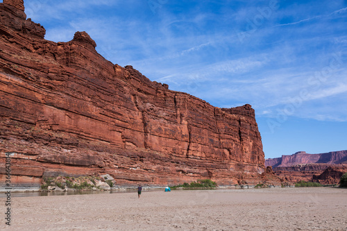A man walks toward a tent in a Utah desert canyon along the Colorado River