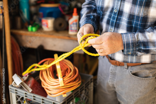 older man handling rope in a garage