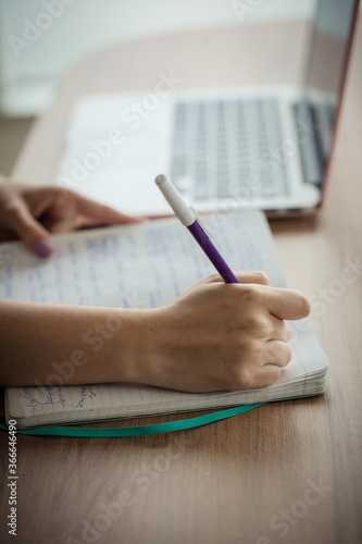 Young female hands working and writing with a notebook and a laptop