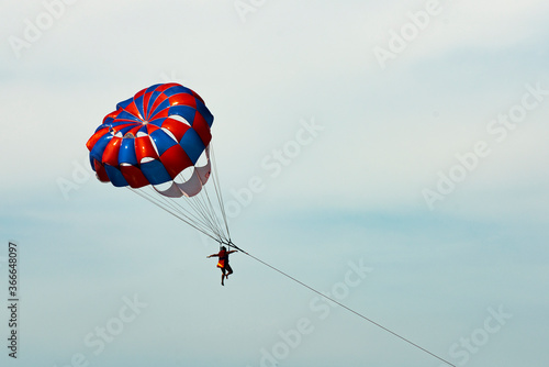 A man on a parachute parachuting over a blue lake.