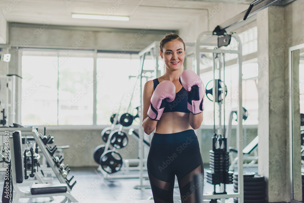 Fototapeta premium Beautiful girls exercise by boxing in the gym. She wears a pink boxing glove and wears exercise.