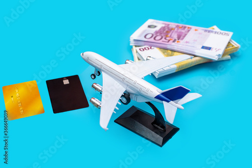 a plane with a wad of cash and plastic cards on a blue background. it symbolizes earnings in air transport, crisis, the cost of tickets for holidays or travel