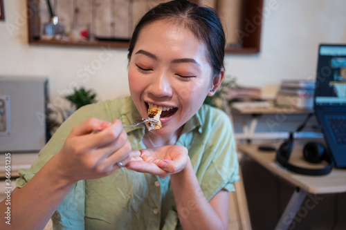 Obraz na płótnie Happy young pretty Asian woman eating delicious chocolate tart on bed w salonie