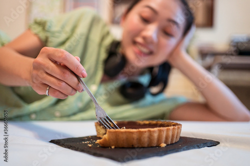Obraz na płótnie Young pretty Asian woman eating delicious chocolate tart lying on bed w salonie