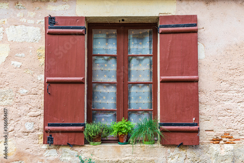 A brown shuttered window on a house in the town of Hautefort.