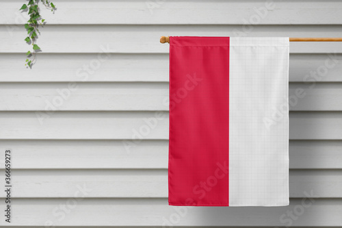 Poland national small flag hangs from a picket fence along the wooden wall in a rural town. Independence day concept.