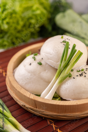 Steamed buns in a wooden dish on a wooden grill.