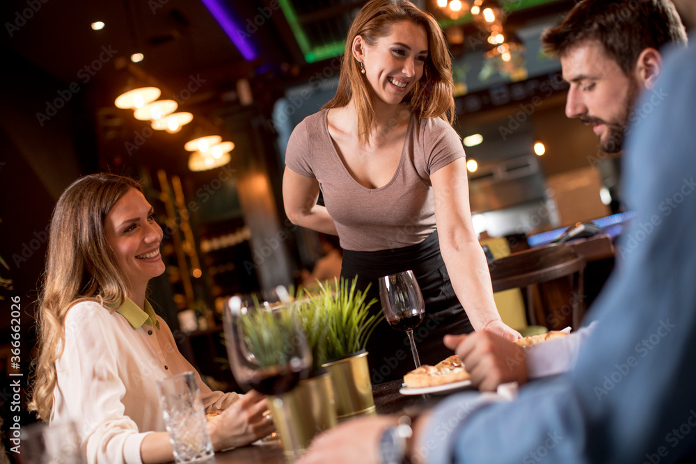 Φωτογραφία Waiter woman serving group of friends with food in the restaurant