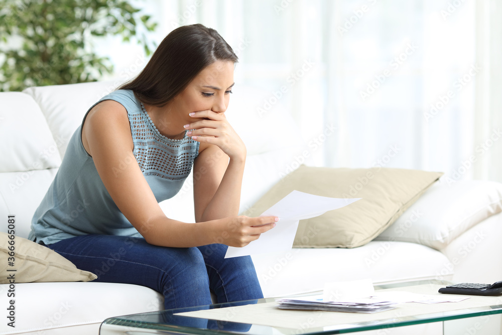 Worried woman reading lettter sitting at home Worried woman reading lettter sitting at home