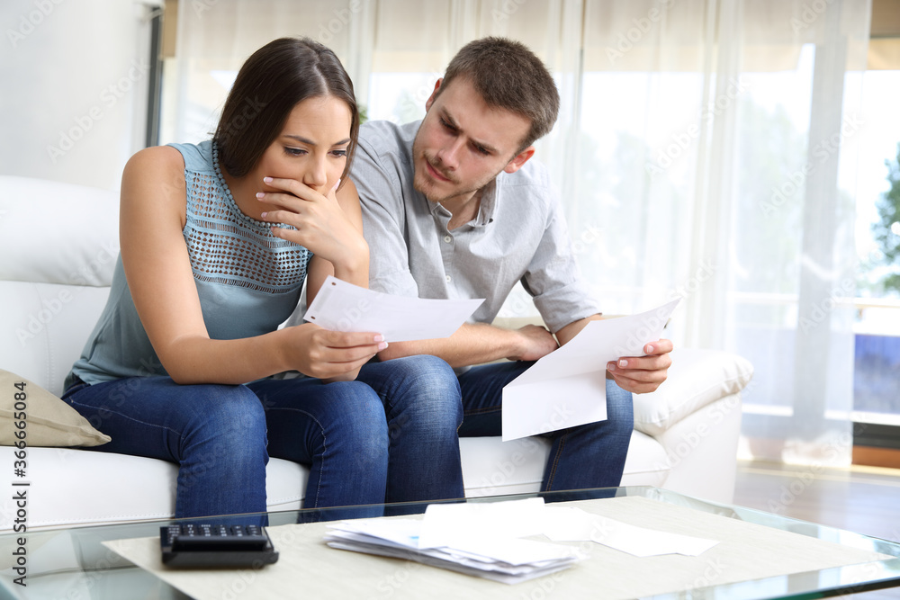 Worried couple checking receipt sitting at home Worried couple checking receipt sitting at home