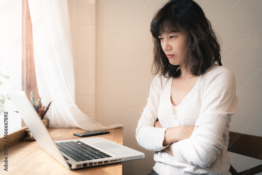 Young Asian worker woman working with laptop computer. A woman thinking of some idea and feeling stress while working from home. Social distancing concept Young Asian worker woman working with laptop computer. A woman thinking of some idea and feeling stress while working from home. Social distancing concept