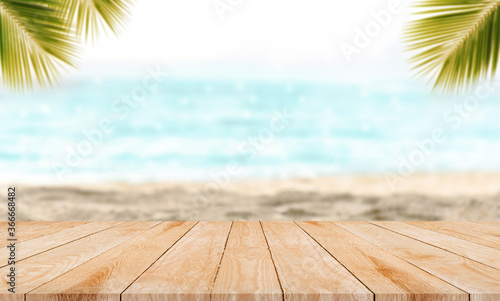 Empty top wooden table with blurred beach and palm leaf background