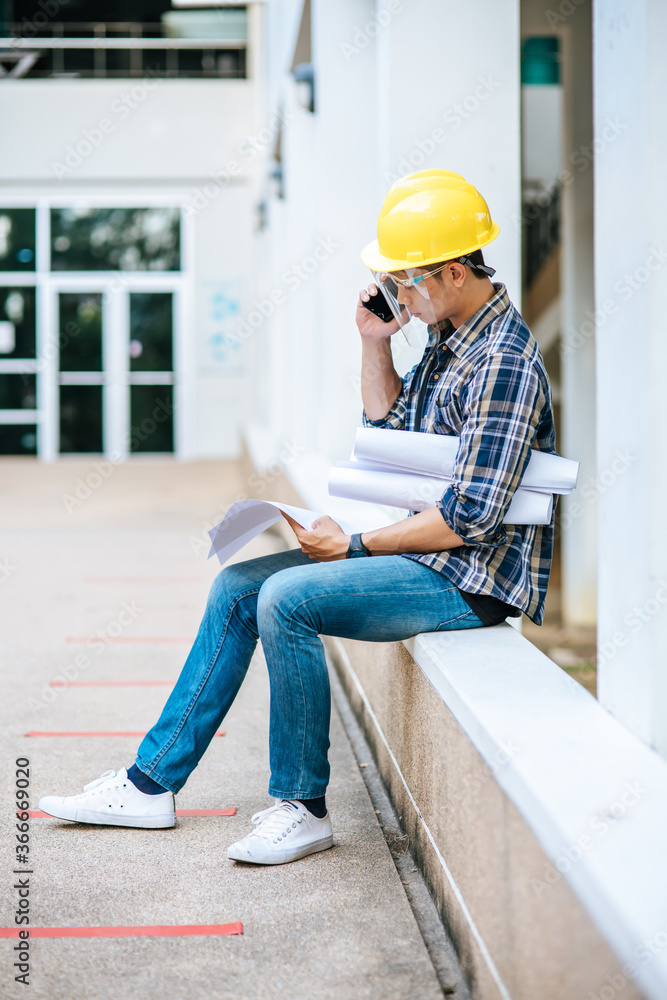 Architects hold floor plans and talk on the phone. Architects hold floor plans and talk on the phone.