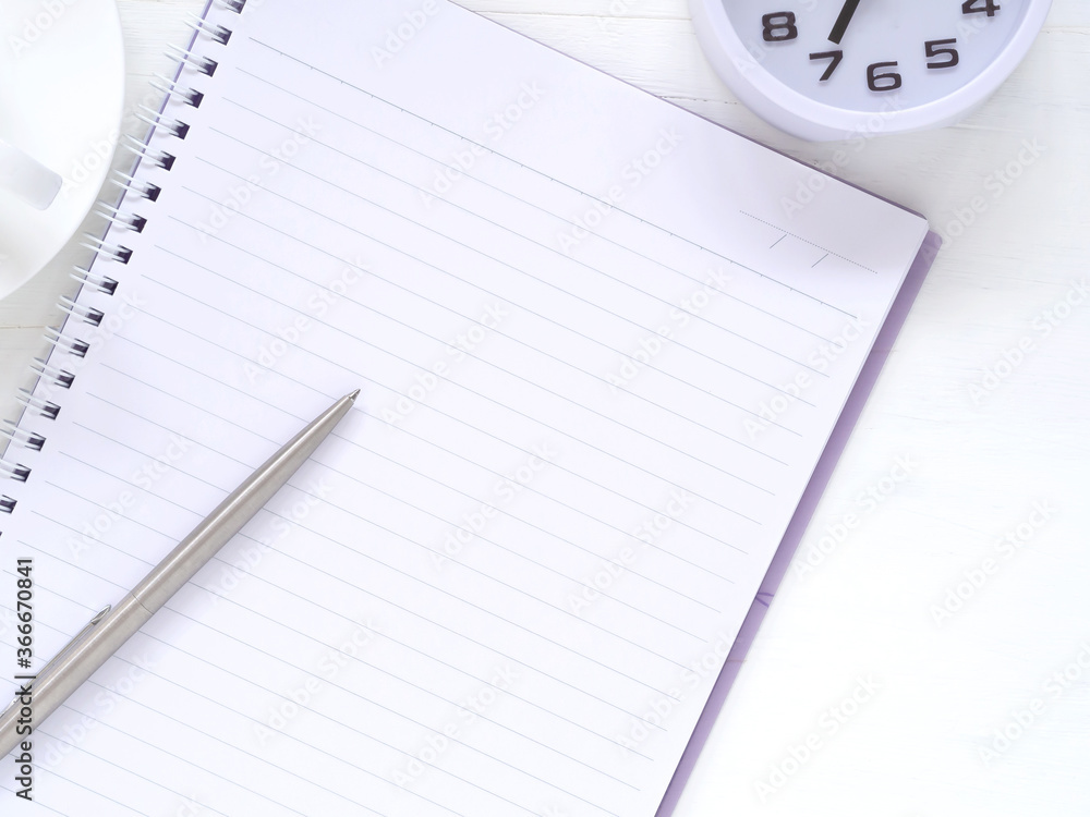 Blank notebook and pen with clock at 7:00 am, coffee cup on white work place desk table. Top view with space for text. Flat lay, Business and education concept.. Blank notebook and pen with clock at 7:00 am, coffee cup on white work place desk table. Top view with space for text. Flat lay, Business and education concept..