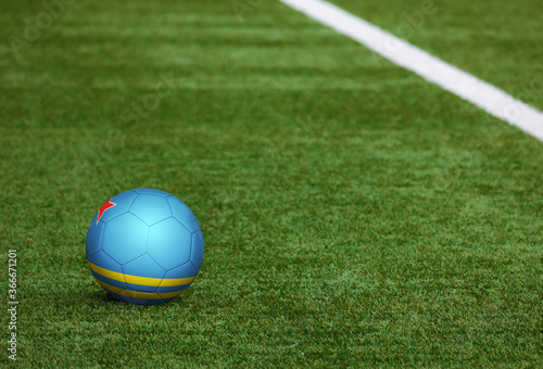 Aruba flag on ball at soccer field background. National football theme on green grass. Sports competition concept.