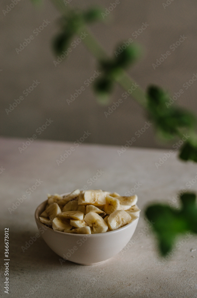 Pretty small ivory bowl with sliced banana on table in the kitchen with mint leaves decoration. Tasty and healthy vegetarian food isolated close up Pretty small ivory bowl with sliced banana on table in the kitchen with mint leaves decoration. Tasty and healthy vegetarian food isolated close up