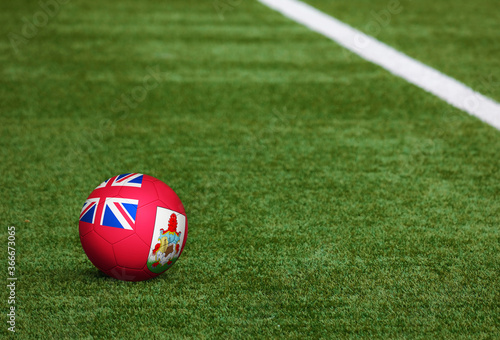 Bermuda flag on ball at soccer field background. National football theme on green grass. Sports competition concept.