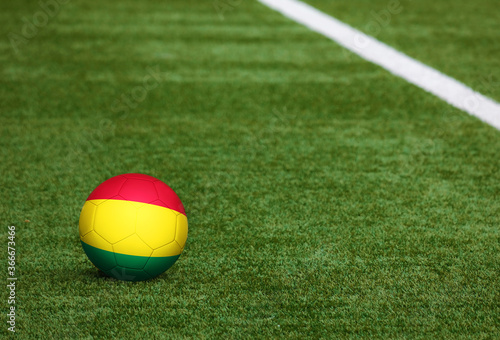 Bolivia flag on ball at soccer field background. National football theme on green grass. Sports competition concept.