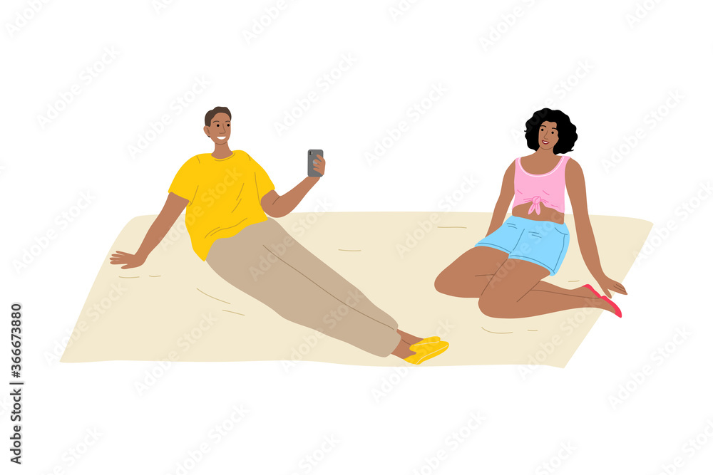 Fototapeta premium Man relaxing on grass and making photo of his girlfriend during summer festival