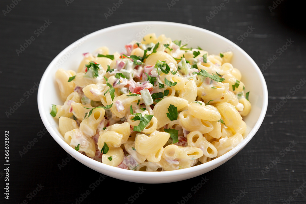 Homemade Macaroni Salad in a white bowl on a black background, side view. Close-up. Homemade Macaroni Salad in a white bowl on a black background, side view. Close-up.