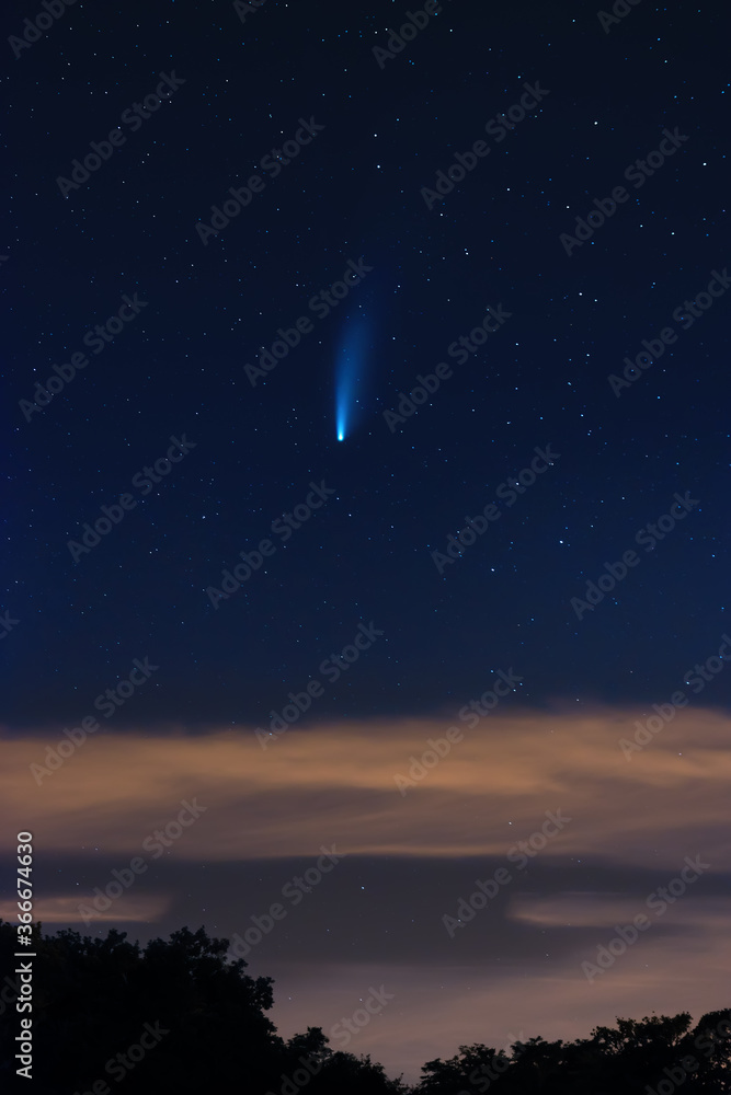 Neowise comet on dark cloudy starry sky