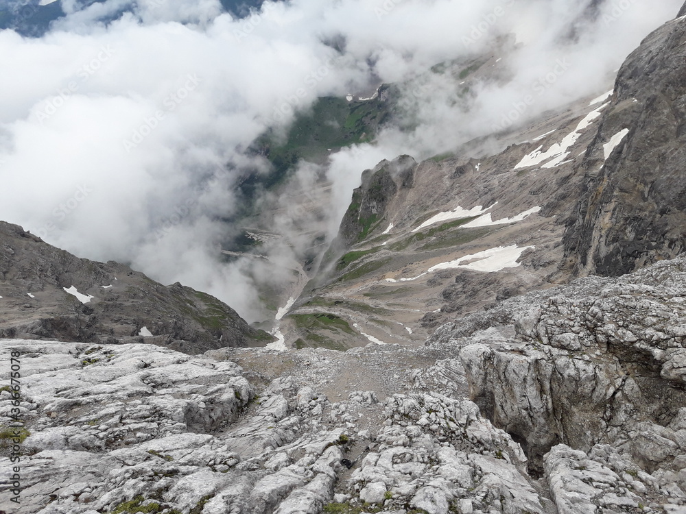 Steep stony mountain slope with white clouds 