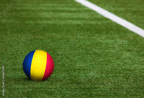 Chad flag on ball at soccer field background. National football theme on green grass. Sports competition concept.