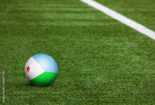 Djibouti flag on ball at soccer field background. National football theme on green grass. Sports competition concept.